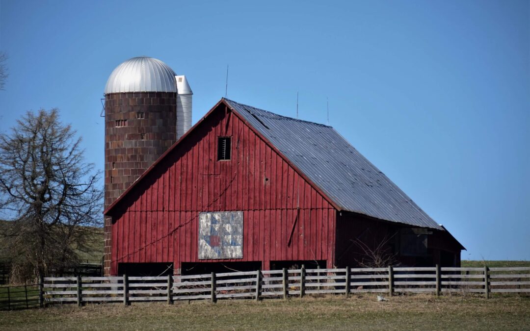 An old red barn surrounded by a fence