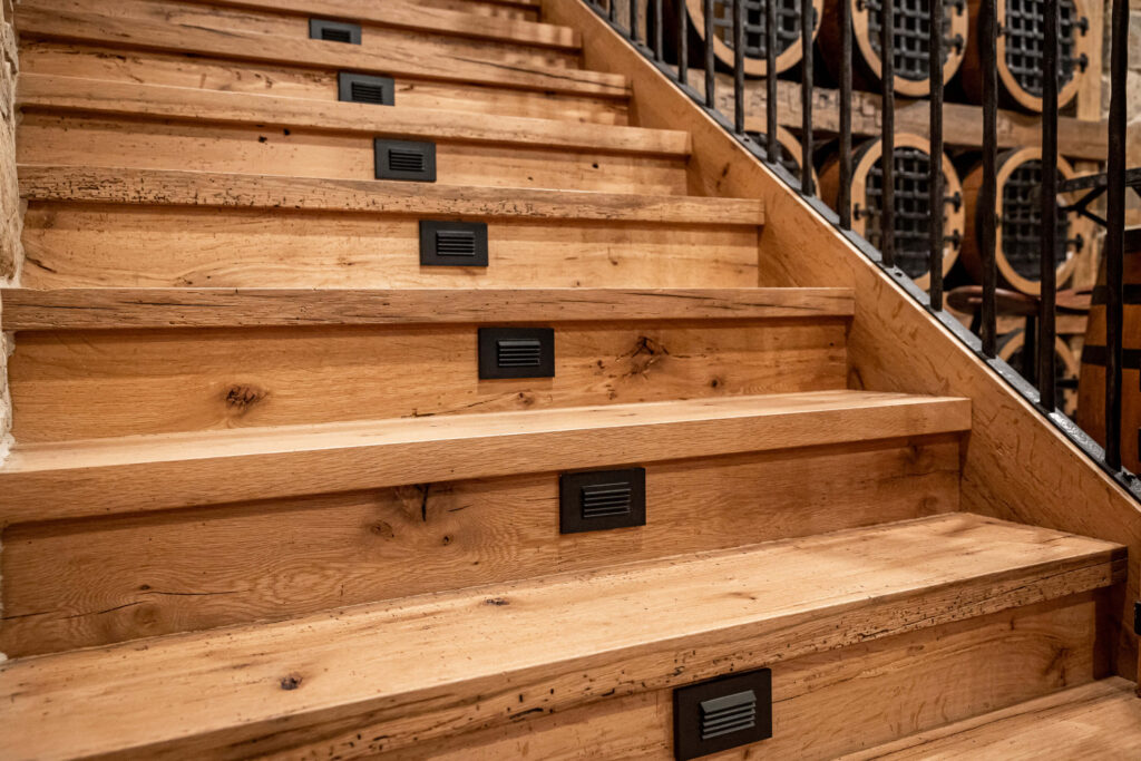 A wooden staircase shows different characteristics of wood such as knots and worm holes.