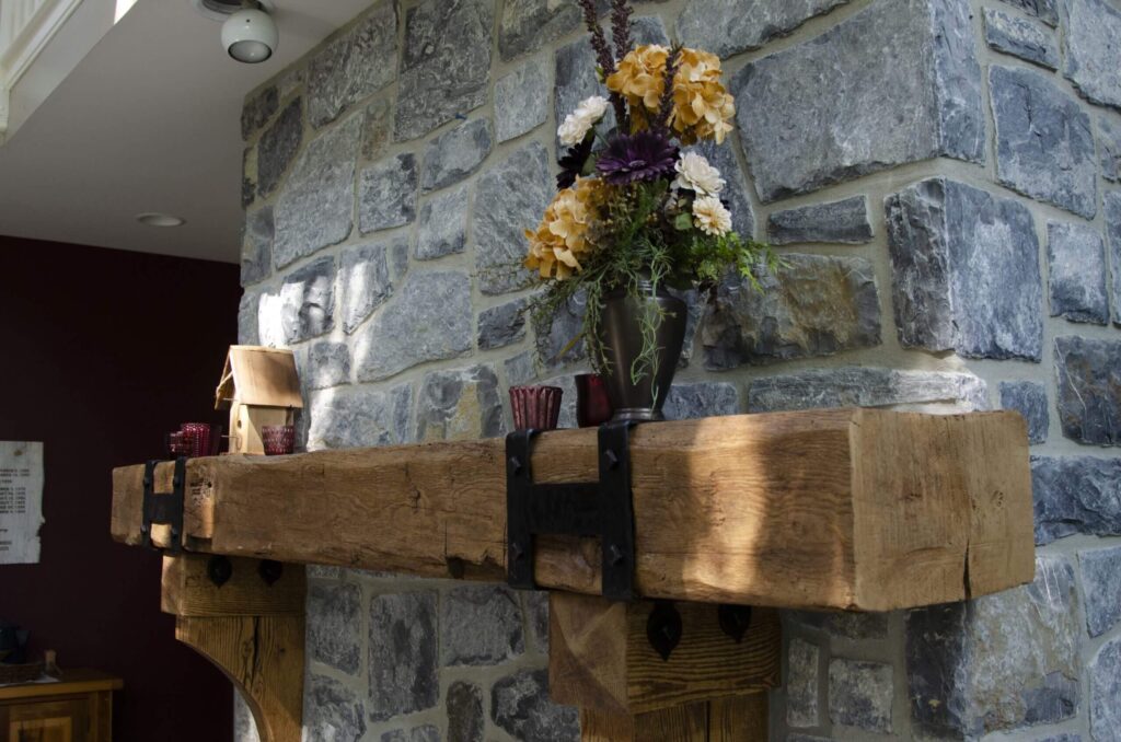 A wooden beam mantel decorated with flowers and vases