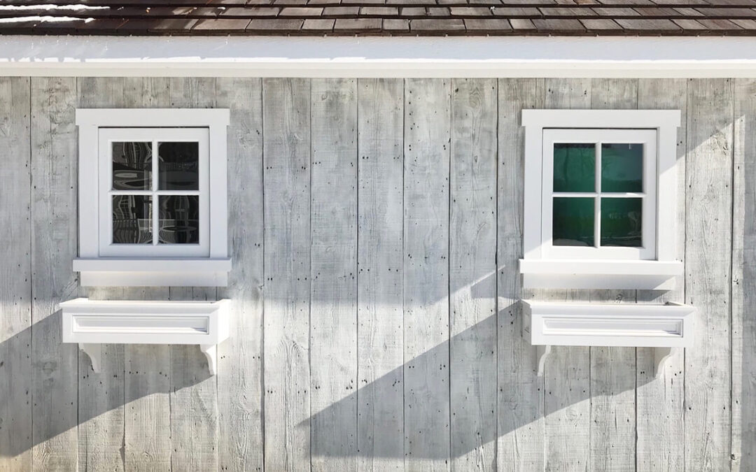 Gray barn wood paneling siding on a shed with two windows